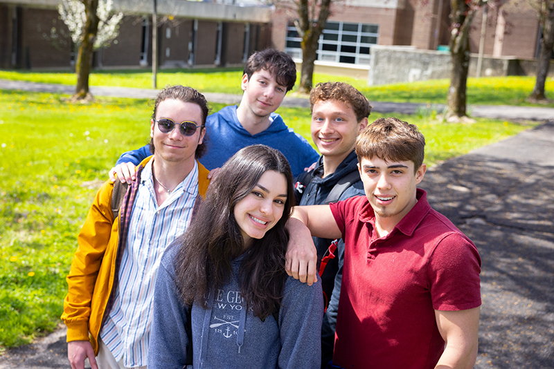 5 happy students pose outdoors on SUNY Ulster campus