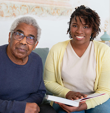 elderly person with younger person reading in a home