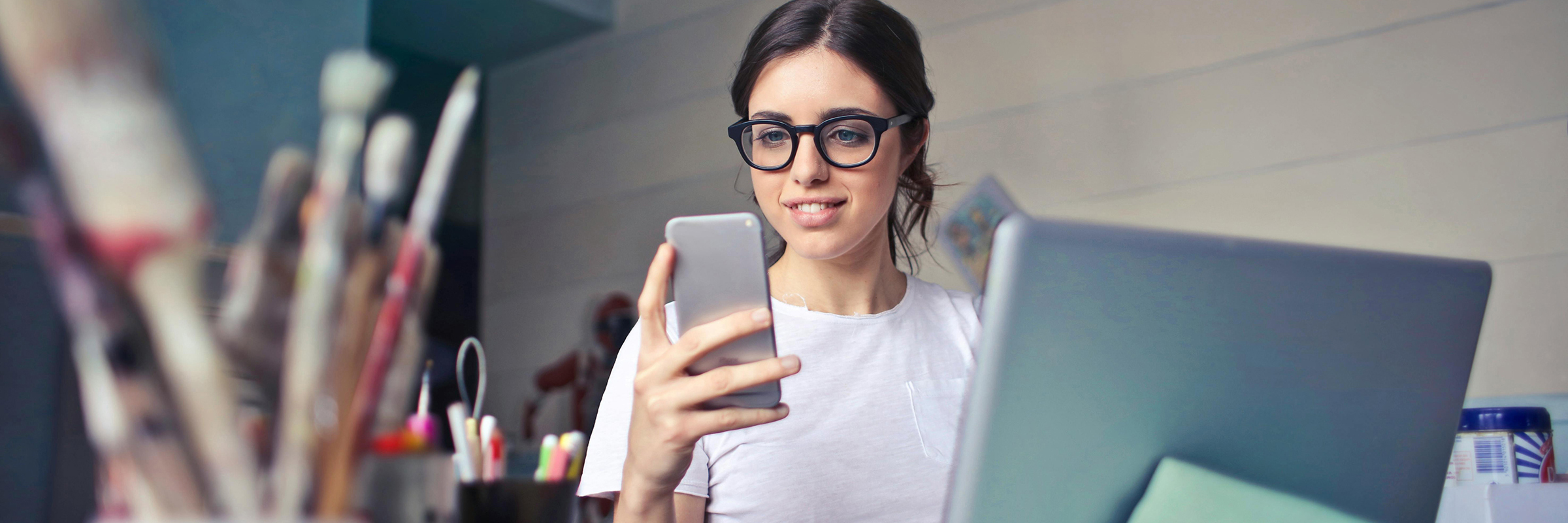 young white woman looking at smartphone while at desk