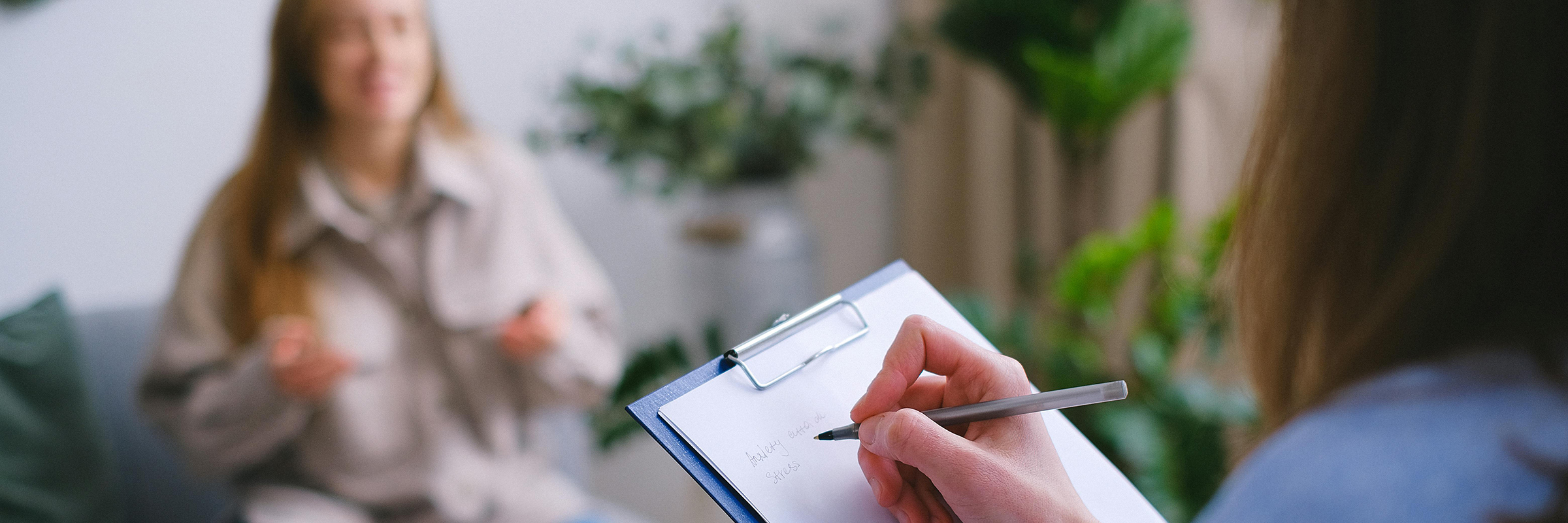 person writing on clipboard during therapy session
