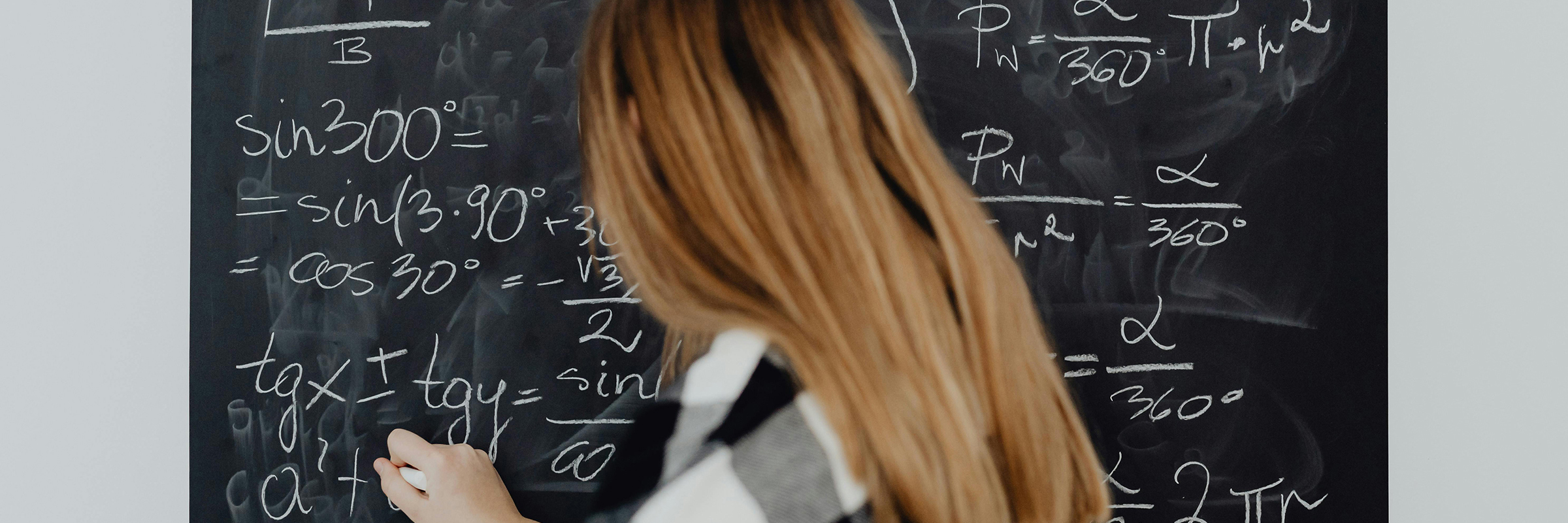 young women writing formulas on black board
