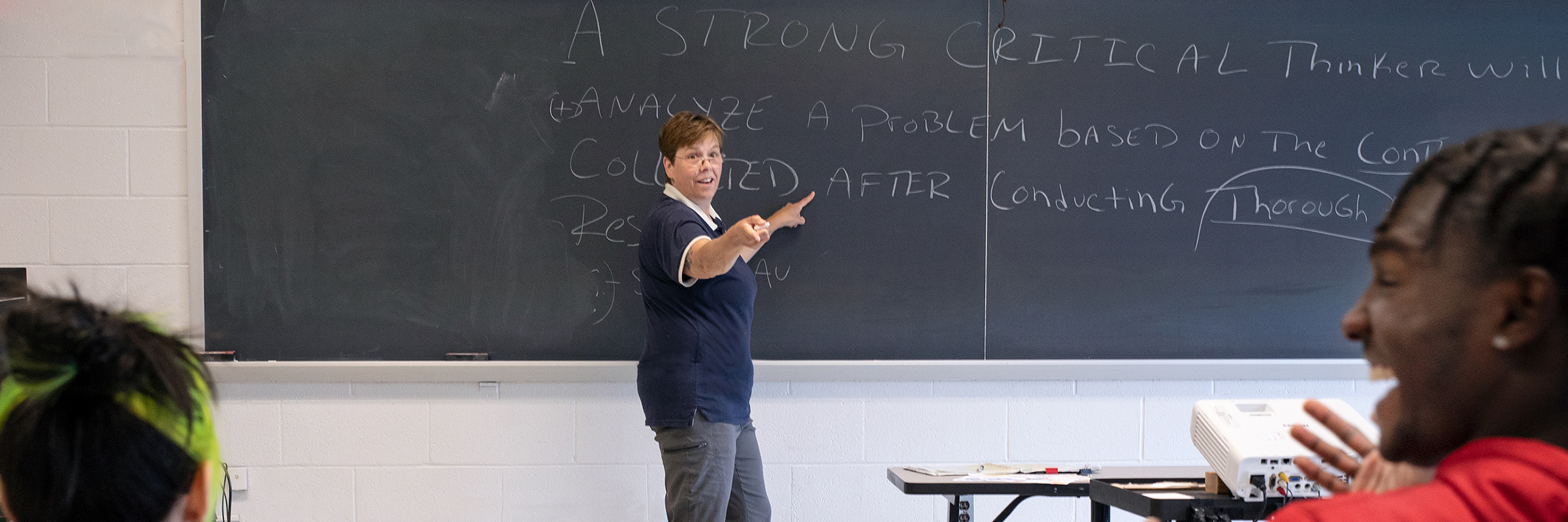 professor pointing at student and chalkboard