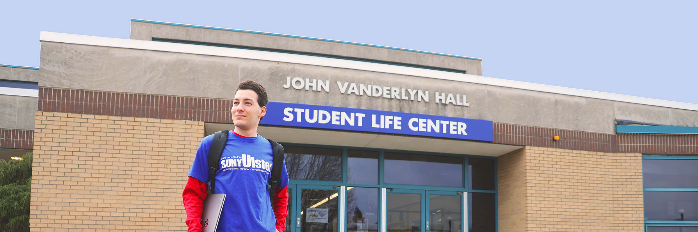 white male student wearing SUNY Ulster shirt in front of vanderlyn Hall